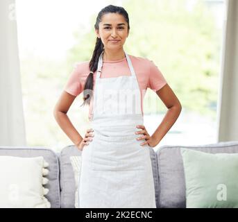 Oggi è giornata di lavoro, quindi domani può essere giornata di relax. Scatto di una giovane donna che indossa un grembiule mentre occupava la pulizia a casa. Foto Stock