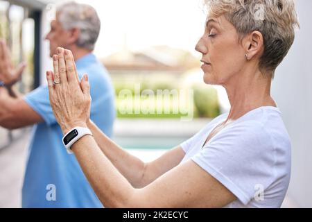 Lo yoga affinerà tutte le vostre percezioni. Scatto di una coppia matura meditando insieme all'aperto. Foto Stock