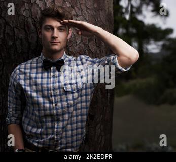 Heres a te. Ritratto di un bel giovane uomo che saluta la macchina fotografica mentre si alza fuori davanti ad un albero. Foto Stock