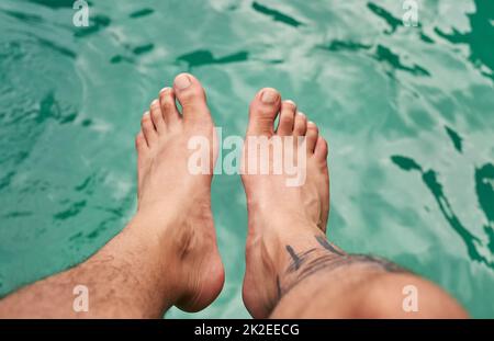 Farsi un'idea dell'acqua. Colpo ad angolo alto di un piede di uomo sopra l'acqua. Foto Stock