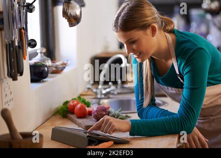 Vediamo cosa posso fare con questi ingredienti. Scatto di una giovane donna che guarda una ricetta online sul suo tablet digitale. Foto Stock