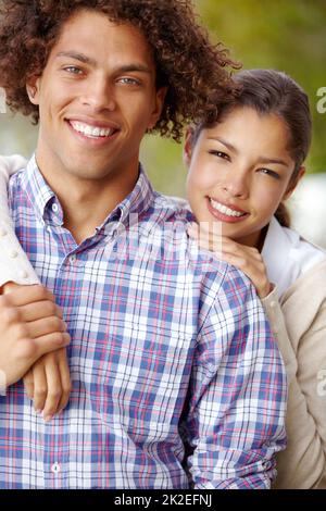 Impegnato in un futuro amorevole. Ritratto di una bella coppia mista di gara sorridendo insieme all'aperto. Foto Stock