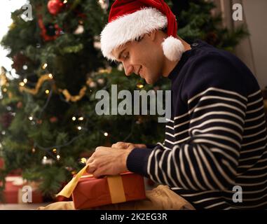 Diffondere lo spirito di Natale. Scatto di un bel giovane uomo che si prepara per Natale. Foto Stock