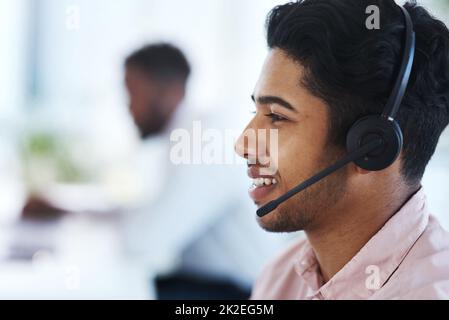 Gestione delle richieste dei chiamanti come un professionista. Scatto di un giovane agente del call center che lavora in ufficio. Foto Stock