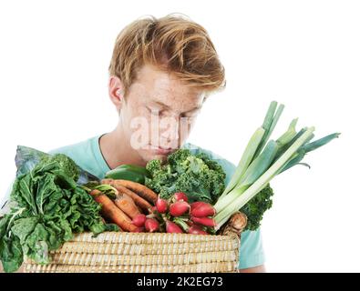 Theres niente come prodotti freschi. Un bel giovane uomo di testa rossa che puzzava un cesto di prodotti vegetali freschi. Foto Stock