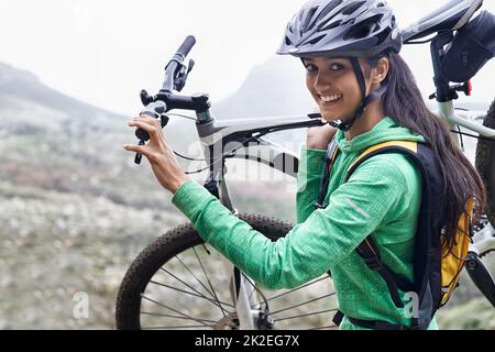 Sono un avventuriero. Una donna piuttosto giovane che porta la sua mountain bike. Foto Stock