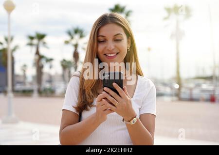 Ragazza turistica in cerca di hotel sul telefono cellulare. Donna che viaggia con il cellulare che prenota una camera per la notte. Concetto di viaggi last minute. Foto Stock