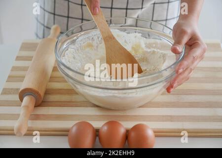 Donna si inginocchia con un cucchiaio di legno in una ciotola a casa, primo piano Foto Stock