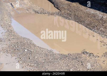 fango e acqua sporca puddddle si è formato sulla strada dopo la pioggia Foto Stock