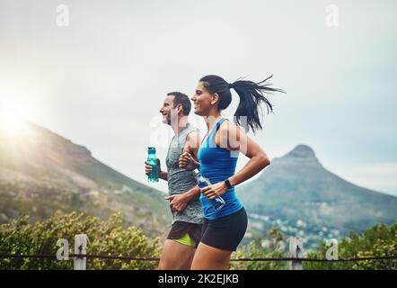 Siamo competitivi in modo amichevole. Scatto di una giovane coppia attraente formazione per una maratona all'aperto. Foto Stock