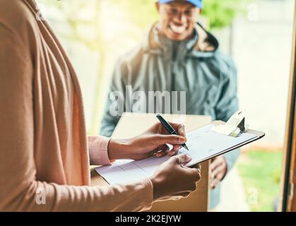 Tutti i thats necessari è una firma semplice. Shot di una donna che firma per la sua consegna dal corriere. Foto Stock