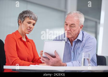 Esaminare il loro business plan. Foto di due colleghi maturi che si siedono con un tablet digitale e discutono di lavoro. Foto Stock