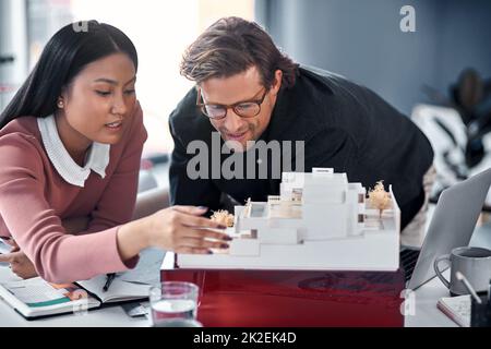 L'attenzione ai dettagli è fondamentale in questo settore. Foto di due giovani architetti che lavorano insieme su un modello in scala di una casa moderna nel loro ufficio. Foto Stock