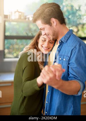 L'amore mette il cuore in una casa. Shot di una giovane coppia affettuosa ballando mano in mano insieme nella loro cucina. Foto Stock