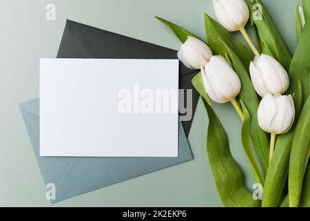 Preparazione per un bigliettino. Carta bianca vuota con busta verde chiaro, modello mock up. Foto Stock