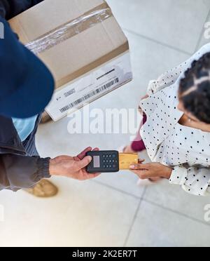 Per la vostra comodità. Colpo ad angolo alto di un uomo di consegna irriconoscibile che riceve il pagamento da una cliente femminile per il suo ordine. Foto Stock