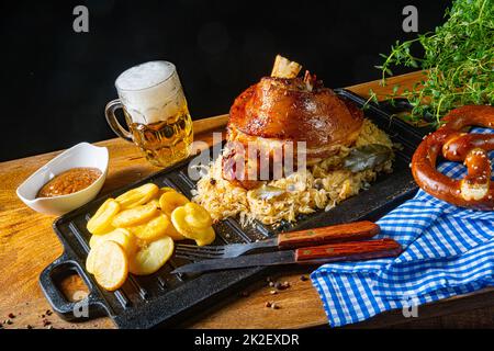 stinco di maiale rustico con crauti, senape dolce e patate fritte Foto Stock