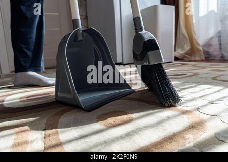 Cleaning.Clean su la spazzatura dal pavimento con una scopa per la pulizia.Sweep via la polvere e lo sporco con una spazzola in un polverpan.Swing il tappeto con una scopa a casa.Indoor strumenti di pulizia. Foto Stock