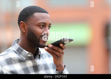 Uomo con pelle nera che usa il riconoscimento vocale sul cellulare Foto Stock