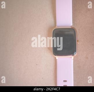 Smart Watch wireless con cinturino rosa isolato su sfondo marrone di carta kraft Foto Stock