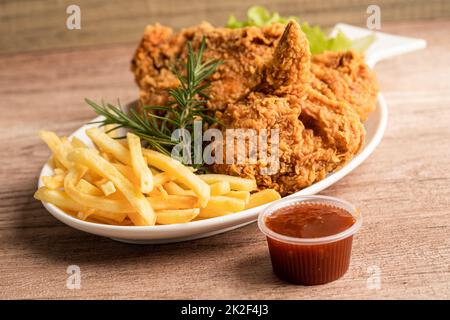 Pollo fritto e patata con foglia di rosmarino, cibo spazzatura ad alto contenuto calorico servito su piatto bianco Foto Stock