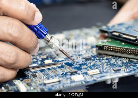 Tecnico che ripara l'interno della scheda a circuito stampato mediante saldatore. Circuito integrato. il concetto di dati, hardware, tecnico e tecnologia. Foto Stock