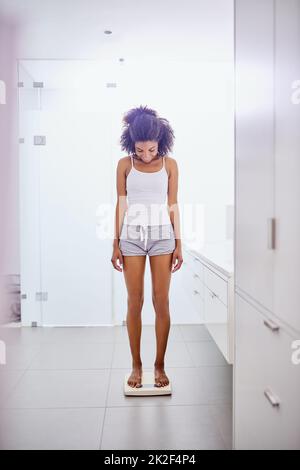 Ora thats che cosa gradisco vedere. Scatto di una giovane donna attraente che si pesa su una bilancia nel bagno di casa. Foto Stock
