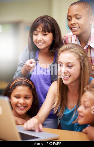 La tecnologia è parte integrante dell'esperienza di apprendimento. Un gruppo di allievi che lavorano su un notebook in classe. Foto Stock