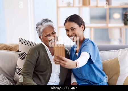 Un po' di divertimento per le loro giornate insieme. Shot di una giovane infermiera che prende selfie con una donna anziana in una casa di riposo. Foto Stock