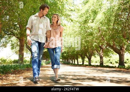 Goditi una passeggiata estiva. Scatto di una coppia matura che si gode una passeggiata nel parco. Foto Stock