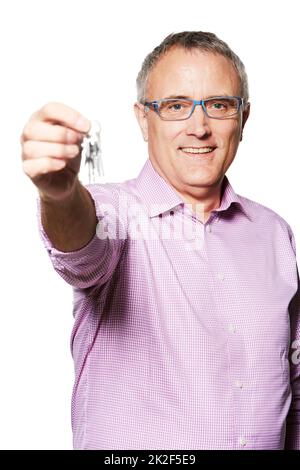 Sono tutti tuoi. Ritratto di studio di un uomo maturo che tiene i tasti fino alla fotocamera. Foto Stock