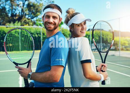 Giocare a tennis è uno stile di vita. Ritratto di due giovani tennisti che si posano insieme in campo. Foto Stock