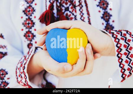 La ragazza ricamata o ricamata mantiene la forma del cuore con la bandiera Ukrane Foto Stock