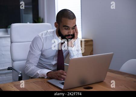 Foto di un uomo d'affari che lavora sul suo computer portatile a tarda notte. Gli uomini d'affari della vita reale hanno girato sul posto. Poiché queste posizioni sono la cosa reale e non sparato in uno studio dell'ufficio, i livelli alti di ISO sono necessari a volte per interferire il momento. L'intervallo ISO è di Foto Stock