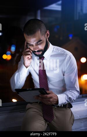 Scatto di un uomo d'affari che parla sul suo cellulare a tarda notte. Gli uomini d'affari della vita reale hanno girato sul posto. Poiché queste posizioni sono la cosa reale e non sparato in uno studio dell'ufficio, i livelli alti di ISO sono necessari a volte per interferire il momento. L'intervallo ISO è Foto Stock