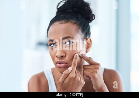 Non ancora tu. Scatto corto di una bella giovane donna che stringe un pimple nello specchio. Foto Stock