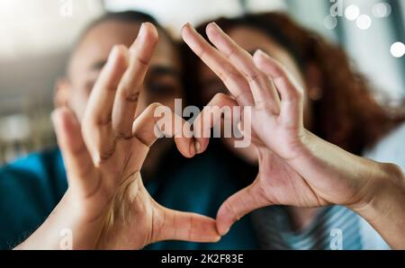 Mi hai completato. Scatto di una giovane coppia che fa un gesto di cuore con le mani all'aperto. Foto Stock