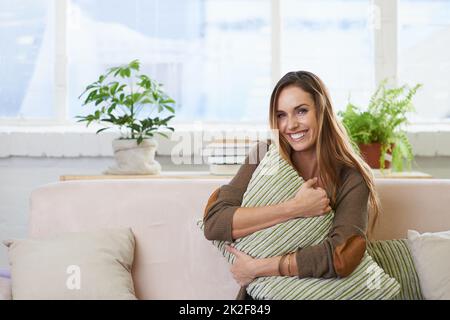 Accoccolarsi con un cuscino. Ritratto corto di una donna attraente rilassante sul divano a casa. Foto Stock