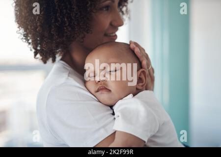 Shh, mamma è qui. Shot di una bambina adorabile che dorme pacificamente nelle braccia delle madri a casa. Foto Stock