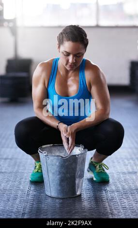 Le mani che le calpano. Scatto a tutta lunghezza di una giovane donna che mette polvere di gesso sulle sue mani in palestra. Foto Stock