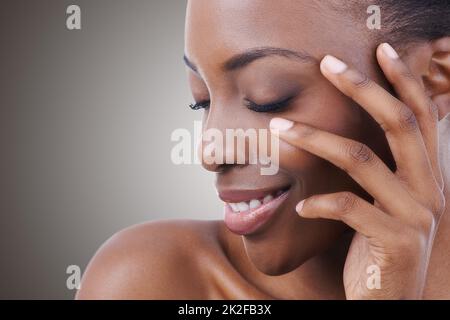 Personalità affascinante come la sua bellezza. Scatto corto di una bella giovane donna che tocca il suo volto con gli occhi chiusi. Foto Stock