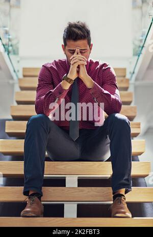 Le cose dovranno migliorare di questo.... Scatto di un giovane uomo d'affari che guarda stressato mentre si siede sulle scale. Foto Stock