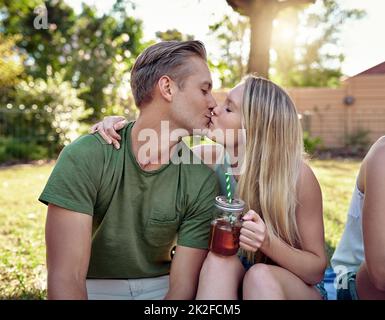 Lasciare che il loro amore vagare libero. Scatto corto di una giovane coppia affettuosa baciare mentre si godono alcune bevande fuori nel sole d'estate. Foto Stock