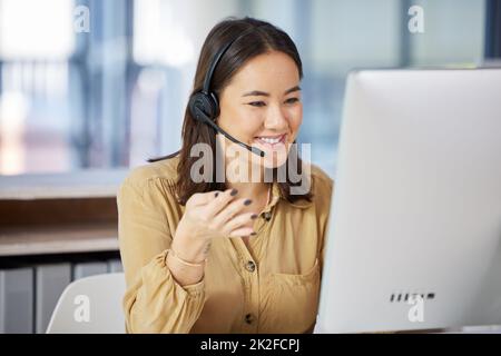 Non teniamo mai i nostri clienti in attesa. Scatto di una giovane donna d'affari che usa un computer mentre lavora in un call center. Foto Stock