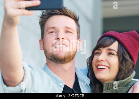 Posso immaginarci fianco a fianco per sempre. Scatto corto di una giovane coppia affettuosa che prende insieme i selfie all'aperto. Foto Stock