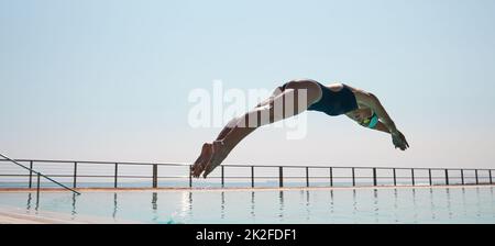 Oggi, hai 100 della tua vita. Shot di un giovane atleta che si tuffa in una piscina di dimensioni olipmiche. Foto Stock