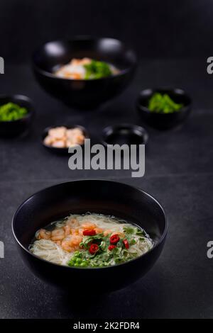 Vari piatti della cucina asiatica con tagliatelle di diversi tipi e riso con gamberi, anatra, verdure e sesamo nero Foto Stock