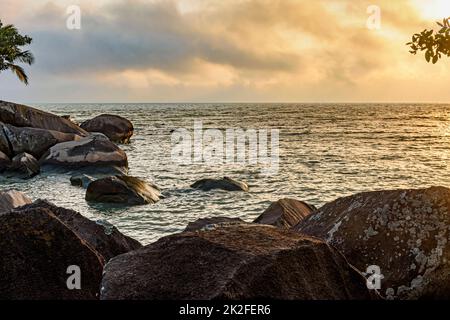Tramonto tropicale tra le rocce nel mare di Ilhabela Foto Stock