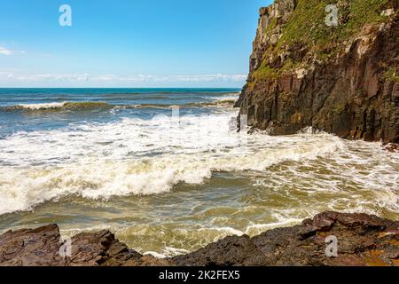 Onde che si schiantano contro un grande muro di roccia Foto Stock