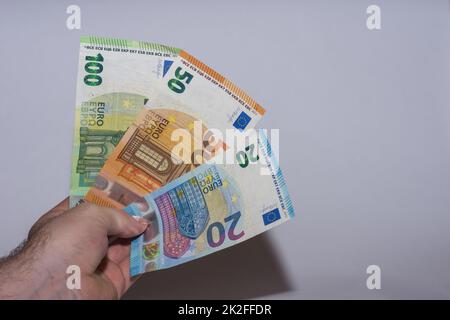 tre banconote in euro tenute in mano con il colore grigio Foto Stock